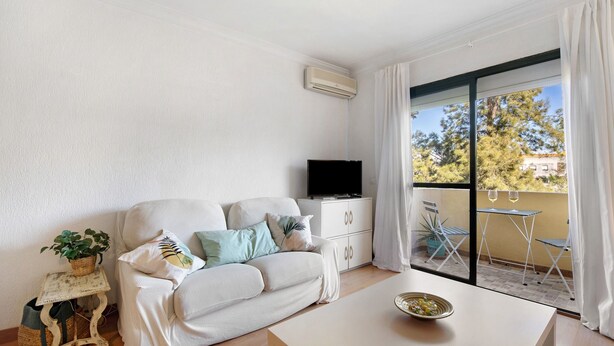 A living room with a sofa, a television, a table, and a balcony with chairs. - Apartment 'Casa Pepe' with Private Terrace, Shared Garden and Wi-Fi (Jerez de la Frontera)