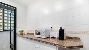 A kitchen with white cabinets, a granite countertop, a microwave, a toaster, and a coffee maker. - Apartment 'Casa Pepe' with Private Terrace, Shared Garden and Wi-Fi (Jerez de la Frontera)