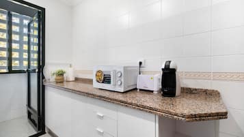 Eine Küche mit weißen Schränken, einer Granit-Arbeitsplatte, einer Mikrowelle, einem Toaster und einer Kaffeemaschine.