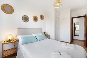 Une chambre à coucher bien rangée, avec un lit, des tables de chevet, une lampe et des éléments décoratifs sur les murs.