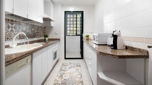 A modern kitchen with white cabinets, a granite countertop, a coffee maker, and a patterned backsplash. - Apartment 'Casa Pepe' with Private Terrace, Shared Garden and Wi-Fi (Jerez de la Frontera)