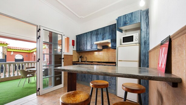 Una cocina con zona de taburetes, microondas y refrigerador.