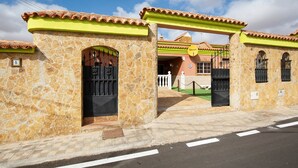 Un edificio de paredes de piedra y tejado de tejas, con una entrada protegida por una reja y un letrero que indica que se trata de un establecimiento comercial.