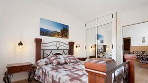 Un dormitorio con una cama, mesitas de noche, un espejo y un cuadro en la pared.