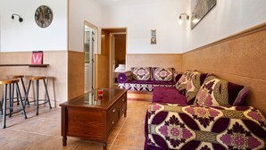 Una sala de estar con sofá, una mesa de centro y una zona de bar con taburetes.