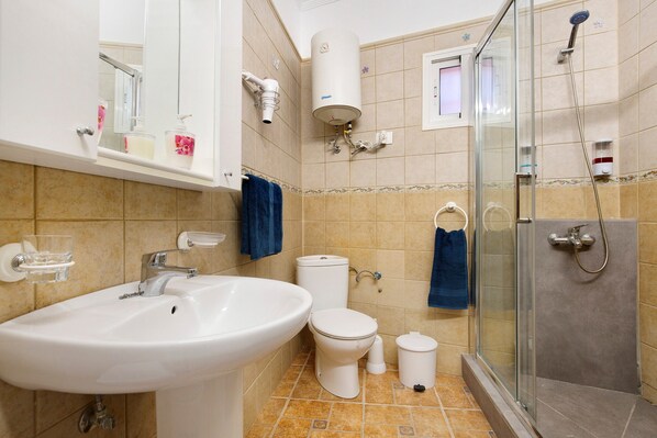 Un baño con lavamanos, inodoro, ducha y cabina de ducha con paredes de vidrio.