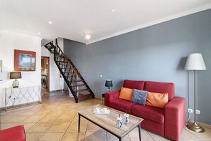 A living room with a red sofa, a wooden coffee table, a staircase, and a floor lamp.
