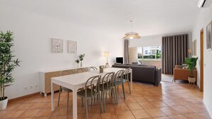 A modern living room with a dining area, a sofa, and a TV.