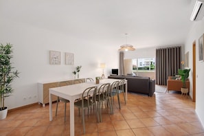 A modern living room with a dining area, a sofa, and a TV.