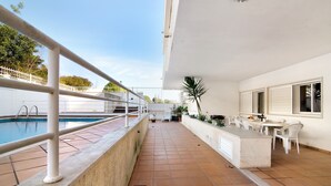A rooftop terrace with a swimming pool, outdoor seating, and a view of the surrounding area.