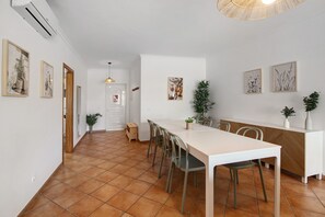 Un espace repas comprenant une longue table, des chaises et un buffet blanc.