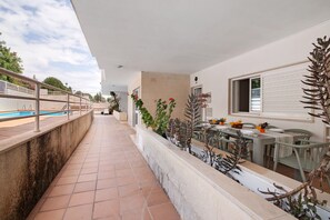 Un espace extérieur abrité comprenant une piscine, une table à manger avec des chaises et des plantes en pot.