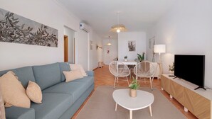Un salon comprenant un canapé, un téléviseur, un coin repas avec des chaises et une table.