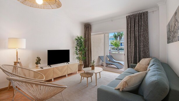 Un salon moderne avec un canapé, un fauteuil, un téléviseur, une lampe et une plante.