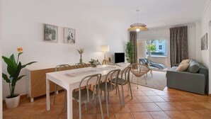 Un salon moderne comprenant un coin repas, un canapé, un téléviseur et une fenêtre avec des rideaux.