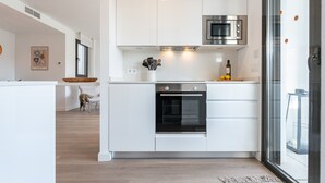 A modern kitchen with white cabinetry, a stainless steel oven, and a microwave.