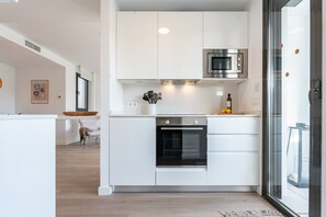 Eine moderne Küche mit weißen Schränken, einem Edelstahlbackofen und einer Mikrowelle.