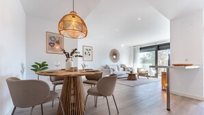 A modern dining area with a round wooden table, four chairs, and a hanging light fixture.