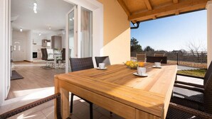 A dining area with a wooden table, wicker chairs, and a fruit bowl.