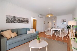 A living room with a sofa, a round table, and two chairs.