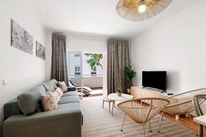 Un salon moderne avec un canapé, des fauteuils, un téléviseur et un balcon offrant une vue agréable.