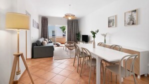 Un salon moderne comprenant un canapé, une table à manger, des chaises, une lampe et des œuvres d’art accrochées aux murs.