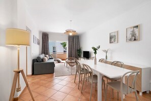 Un salon moderne comprenant un canapé, une table à manger, des chaises, une lampe et des œuvres d’art accrochées aux murs.