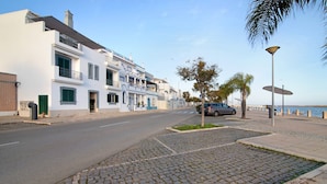 A coastal street with a paved sidewalk, a parked car, and buildings with balconies. - Holiday Apartment "Estrela Do Mar" with Wi-Fi (Santa Luzia)