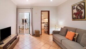 A living room with a television, sofa, and artwork on the wall. - Holiday Apartment "Estrela Do Mar" with Wi-Fi (Santa Luzia)