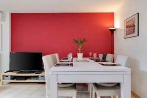 A dining area with a white table, red wall, and a potted plant. - Holiday Home 'In Bordeaux, Air-Conditioned with Pool Table' with Private Terrace and AC (Le Bouscat)