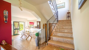A spacious living area with a staircase leading to an upper floor, a dining area, and a kitchen. - Awesome home in Caronia (Caronia)