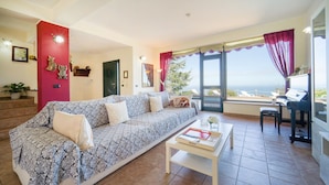 A living room with a patterned sofa, a coffee table, and a view of the sea. - Awesome home in Caronia (Caronia)