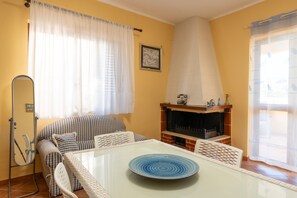 Una sala de estar con un sofá, una mesa de vidrio, una chimenea y una ventana con cortinas.