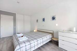 Ein Schlafzimmer mit Bett, Nachttisch, Sessel, Kommode und Bildern an der Wand.