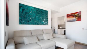 A modern living room with a sectional sofa, a teal abstract painting, and a red abstract painting. - Apartamento Da Alegria – Feel at Home on the Silver Coast (Caldas da Rainha)