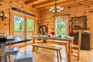 A wooden cabin interior with a dining area, a kitchen counter, and a fireplace. - Free Dollywood Tix/Dog Friendly/Gameroom/HotTub/ (Sevierville)