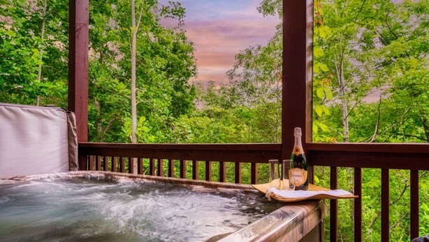 Ein Whirlpool mit einer Holterrasse und einer Champagnerflasche auf einem Tablett.
