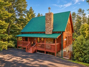 A lodge with a green roof, stone chimney, wooden exterior, and a porch with steps leading to the entrance. - Free Dollywood Tix/Dog Friendly/Gameroom/HotTub/ (Sevierville)