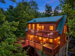 A two-story wooden cabin with a balcony, surrounded by trees. - Free Dollywood Tix/Dog Friendly/Gameroom/HotTub/ (Sevierville)