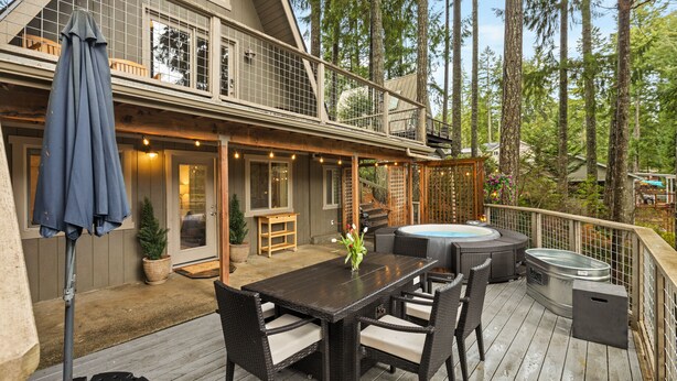 A deck with a table and chairs, a hot tub, and a covered seating area. - Stylish Lakefront Cabin Retreat, Sauna/Hot tub & Cold Plunge (Gig Harbor)