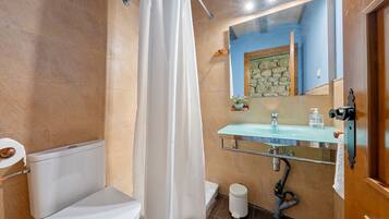 Une salle de bain équipée de toilettes, d’un rideau de douche, d’un lavabo et d’un miroir.