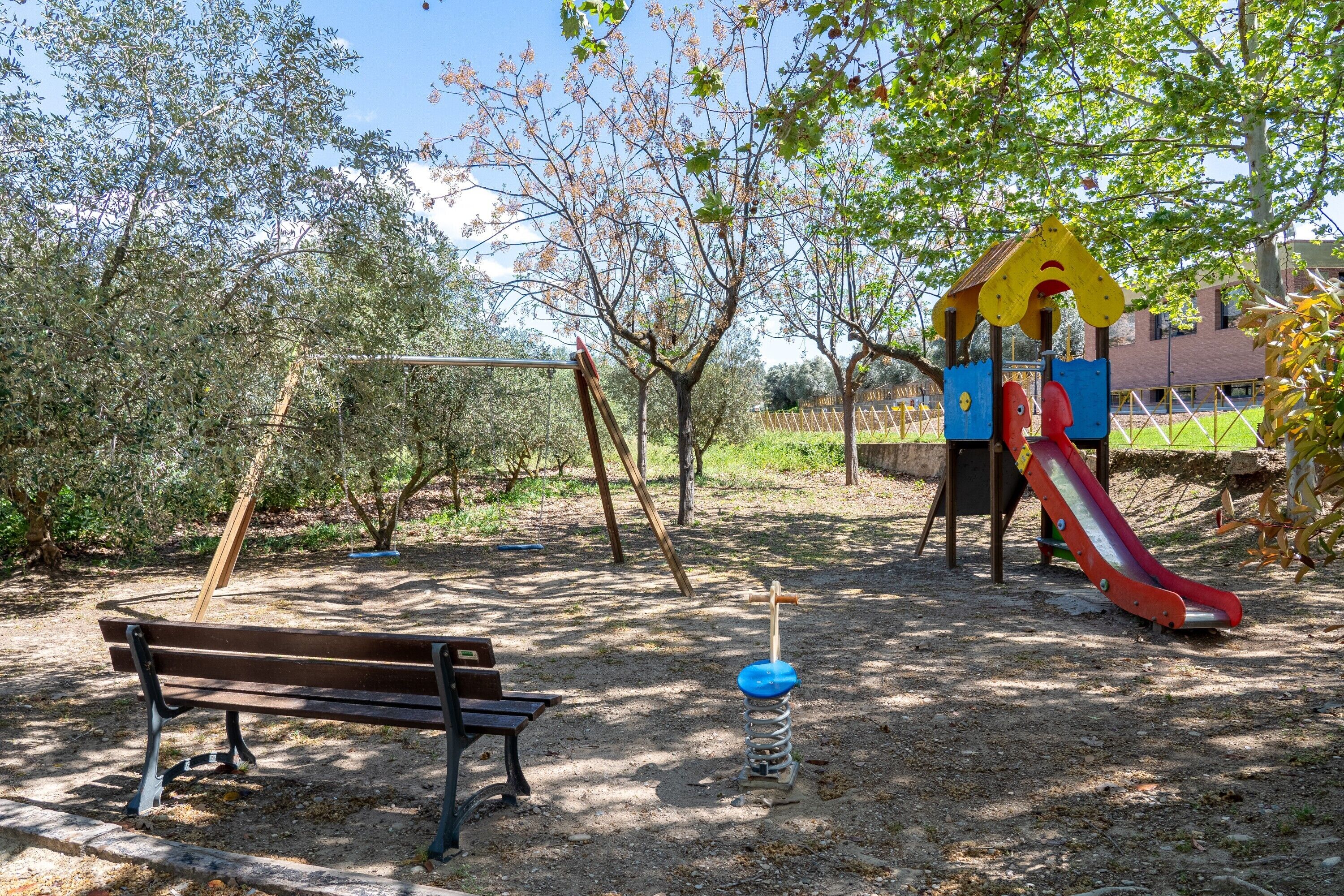 A playground with a slide, swings, and a bench.
