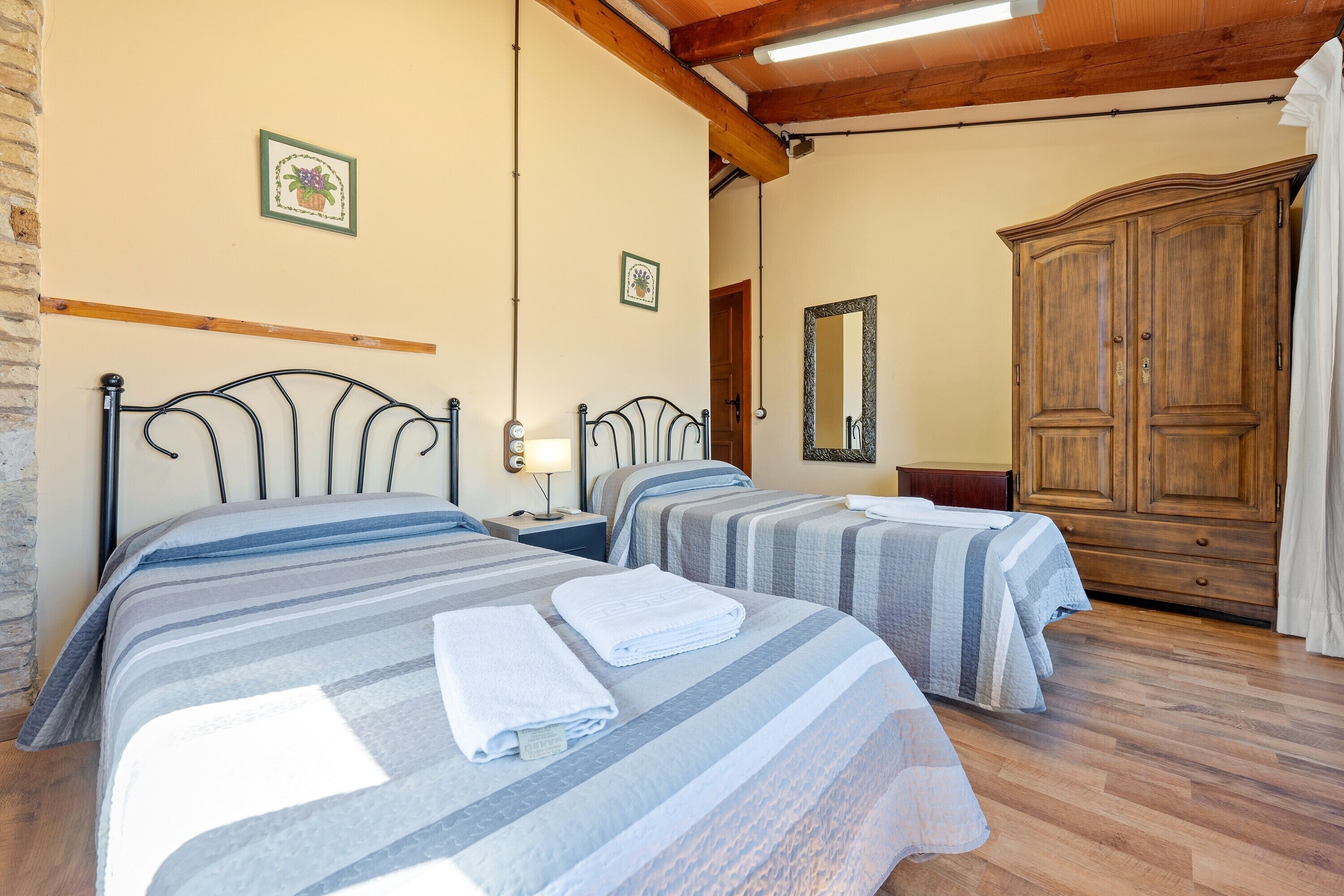 Habitación de hotel con dos camas, un armario de madera y un espejo.