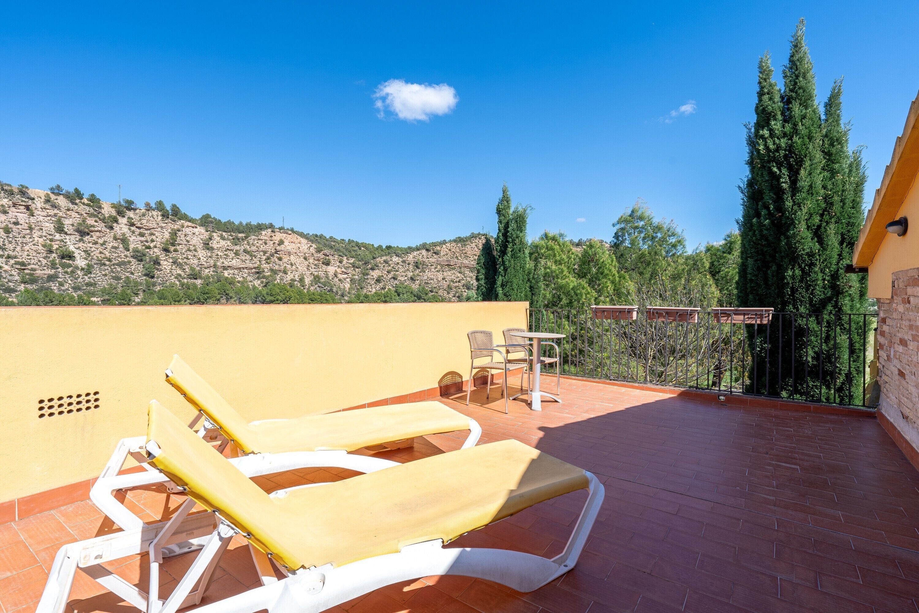 Une terrasse avec deux chaises longues, une table et des chaises.