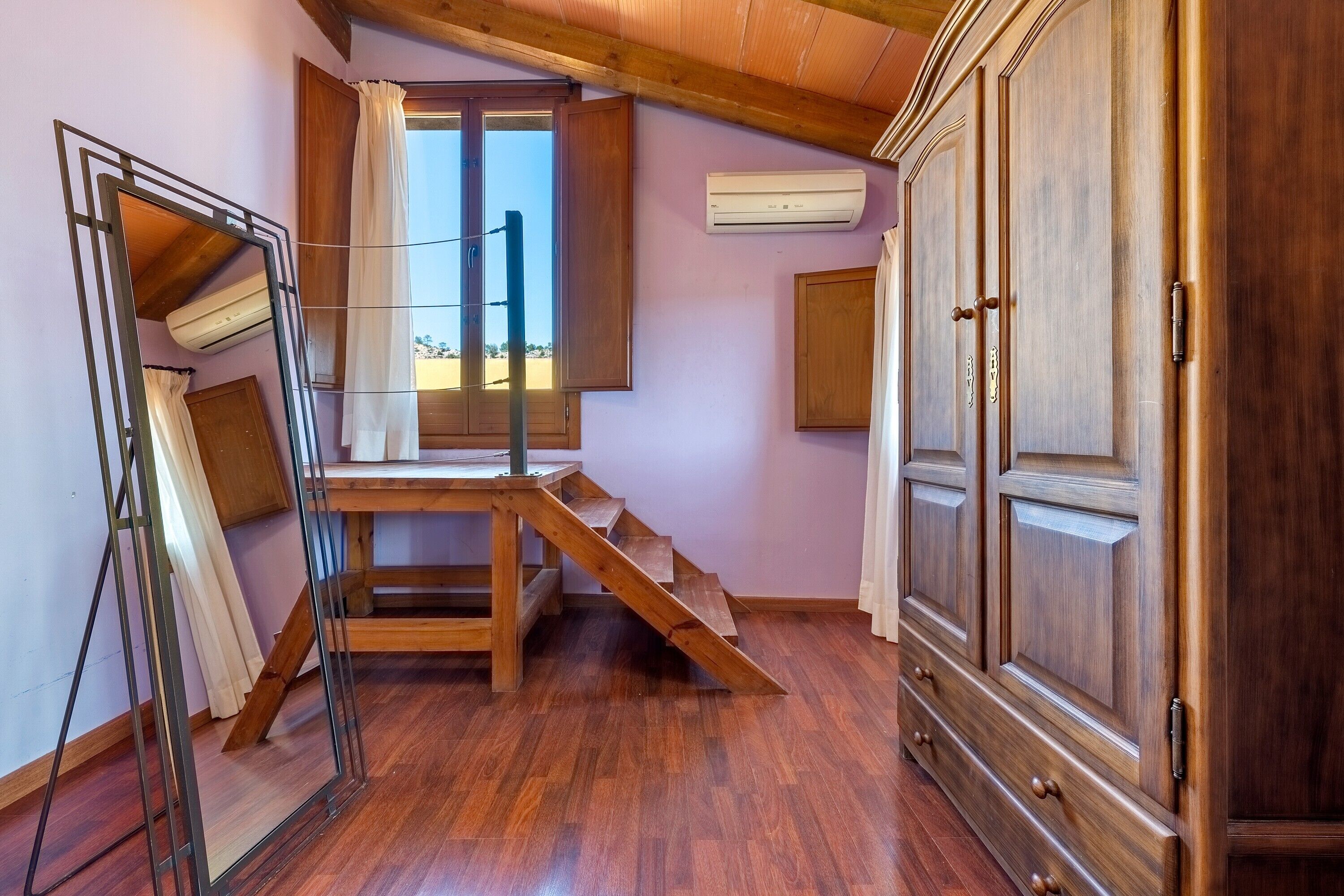 Una stanza con una scala in legno, un armadio grande e un condizionatore d'aria a parete.