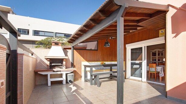 Un'area patio con una griglia barbecue, un tavolo e una zona salotto coperta.