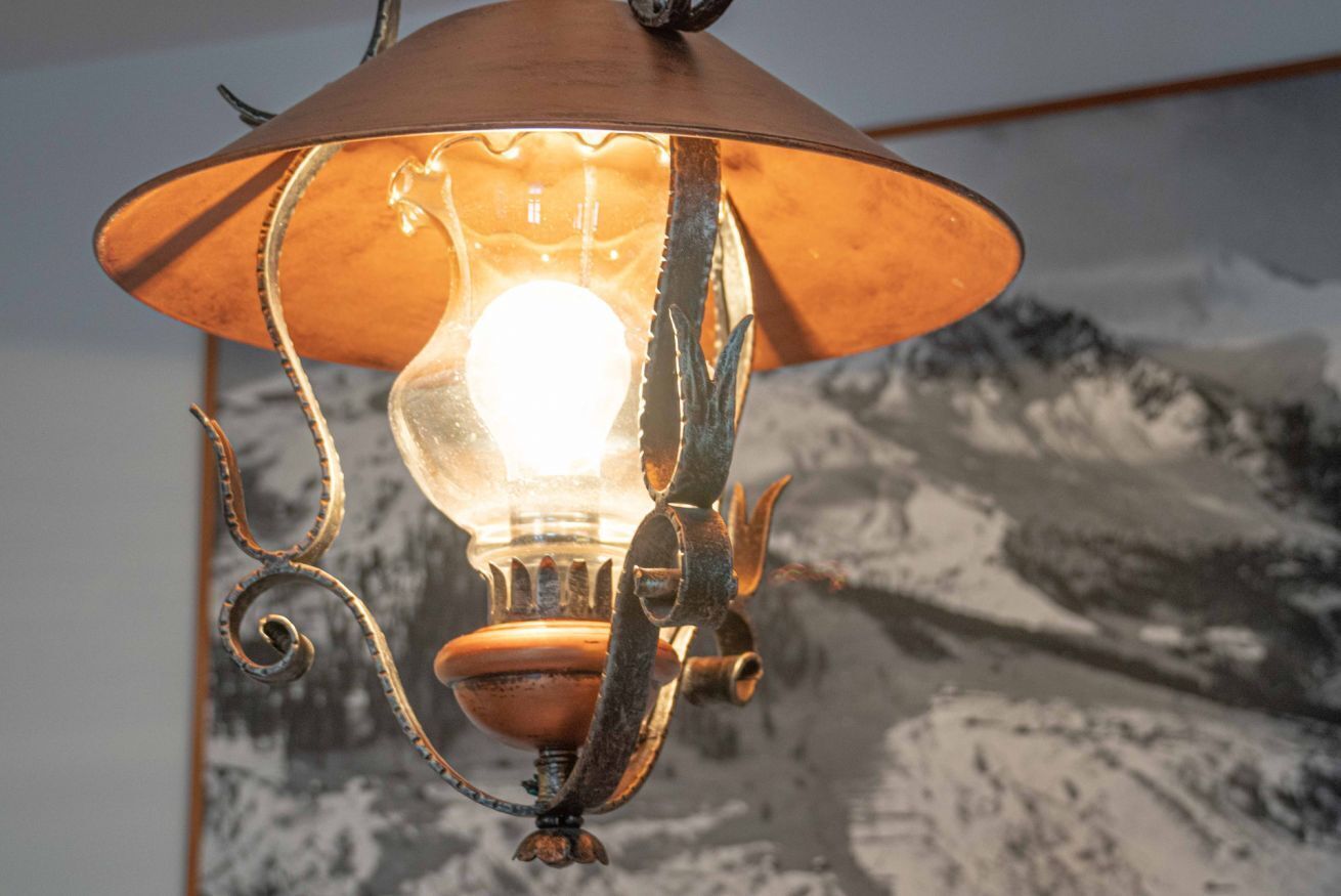 Lampada da parete in stile vintage con paralume in vetro trasparente e lampadina a vista.