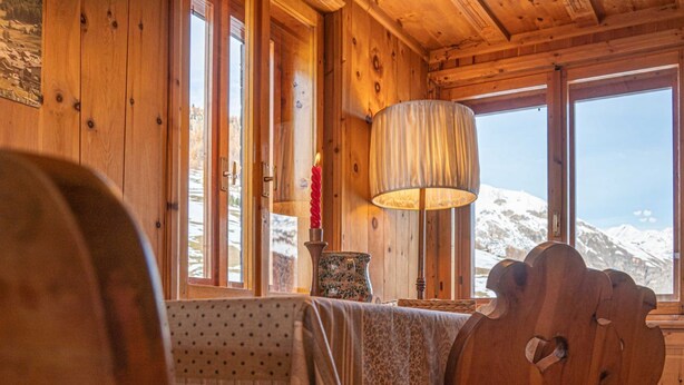 A cozy wooden cabin interior with a large window offering a snowy mountain view. - Typical wooden apartment, warm and cozy suitable for a large family (Livigno)