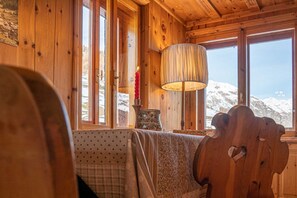 A cozy wooden cabin interior with a large window offering a snowy mountain view. - Typical wooden apartment, warm and cozy suitable for a large family (Livigno)