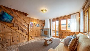 A wooden interior with a sofa, a fireplace, and a staircase. - Typical wooden apartment, warm and cozy suitable for a large family (Livigno)